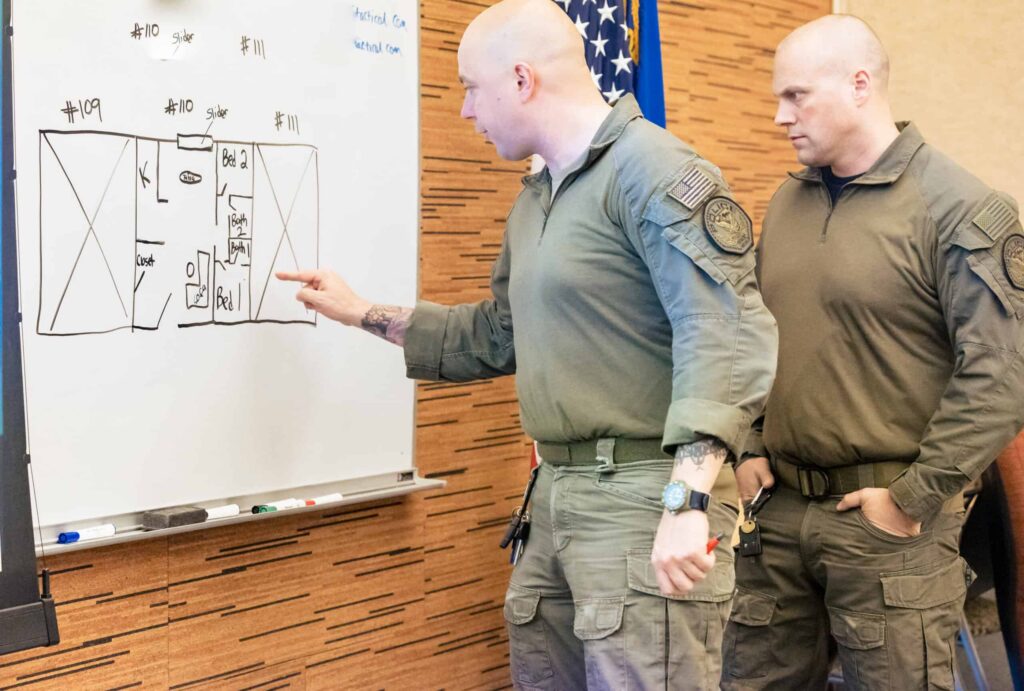Two SWAT officers drawing floor plans during a tabletop exercise at Grey Group hostage rescue training.