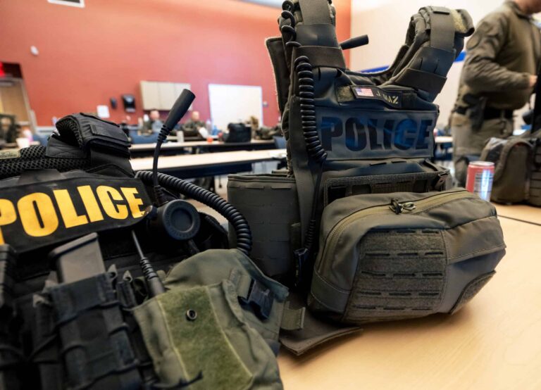 Two SWAT operators discussing different tactical vest setups during Grey Group hostage rescue training.