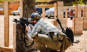 Law enforcement student practicing kneeling barricade position with LPVO-equipped patrol rifle during instructor training