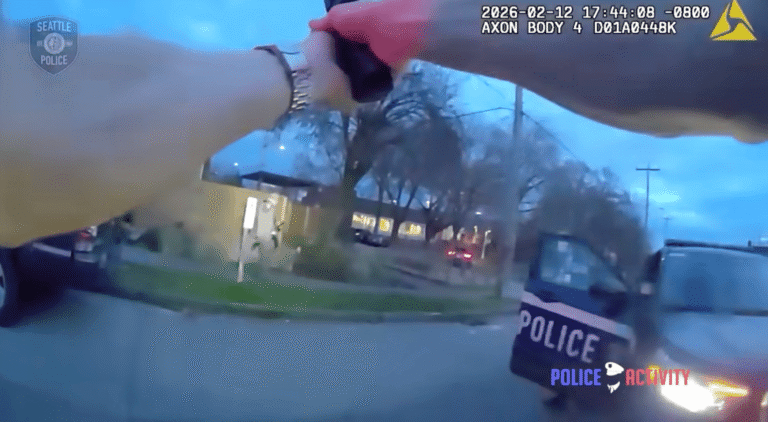 Police officer exposed without cover during armed encounter with suspect near patrol vehicles.