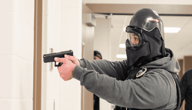 School resource officer practicing active threat response with a firearm in a training session.