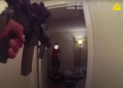 Police officer under fire from armed suspect during building search illustrating CQB vs patrol reality training risks.