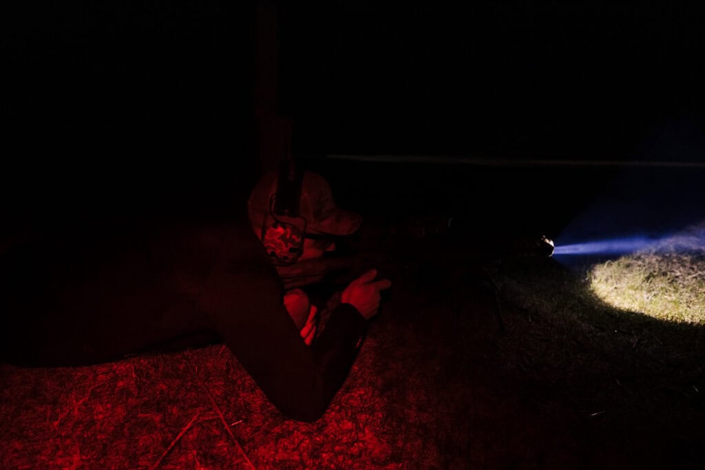 Student uses a weapon-mounted light during low-light training, with the beam directed at the ground.